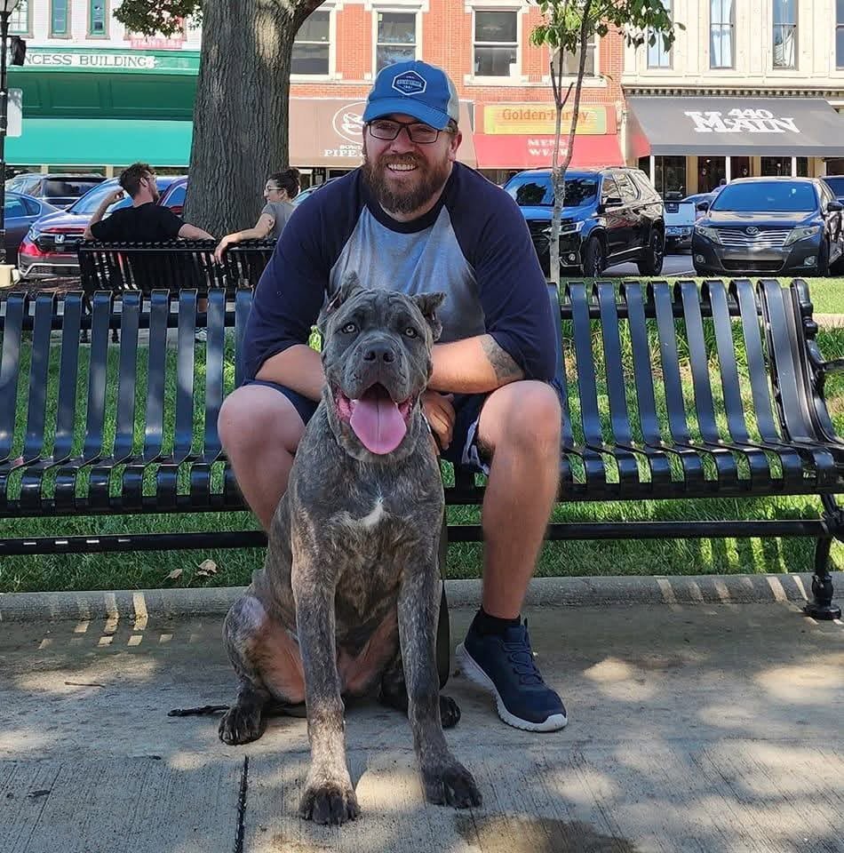 Ben on a park bench with a large grey dog sitting in front of him