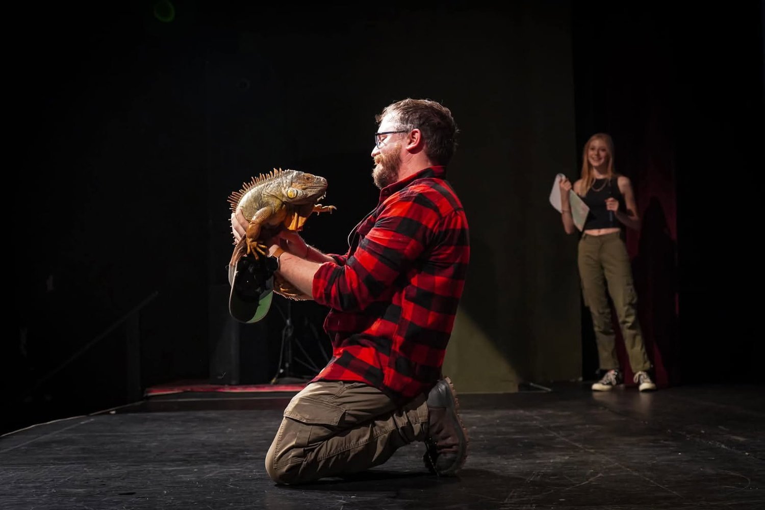 Ben on stage during a live presentation, holding an iguana